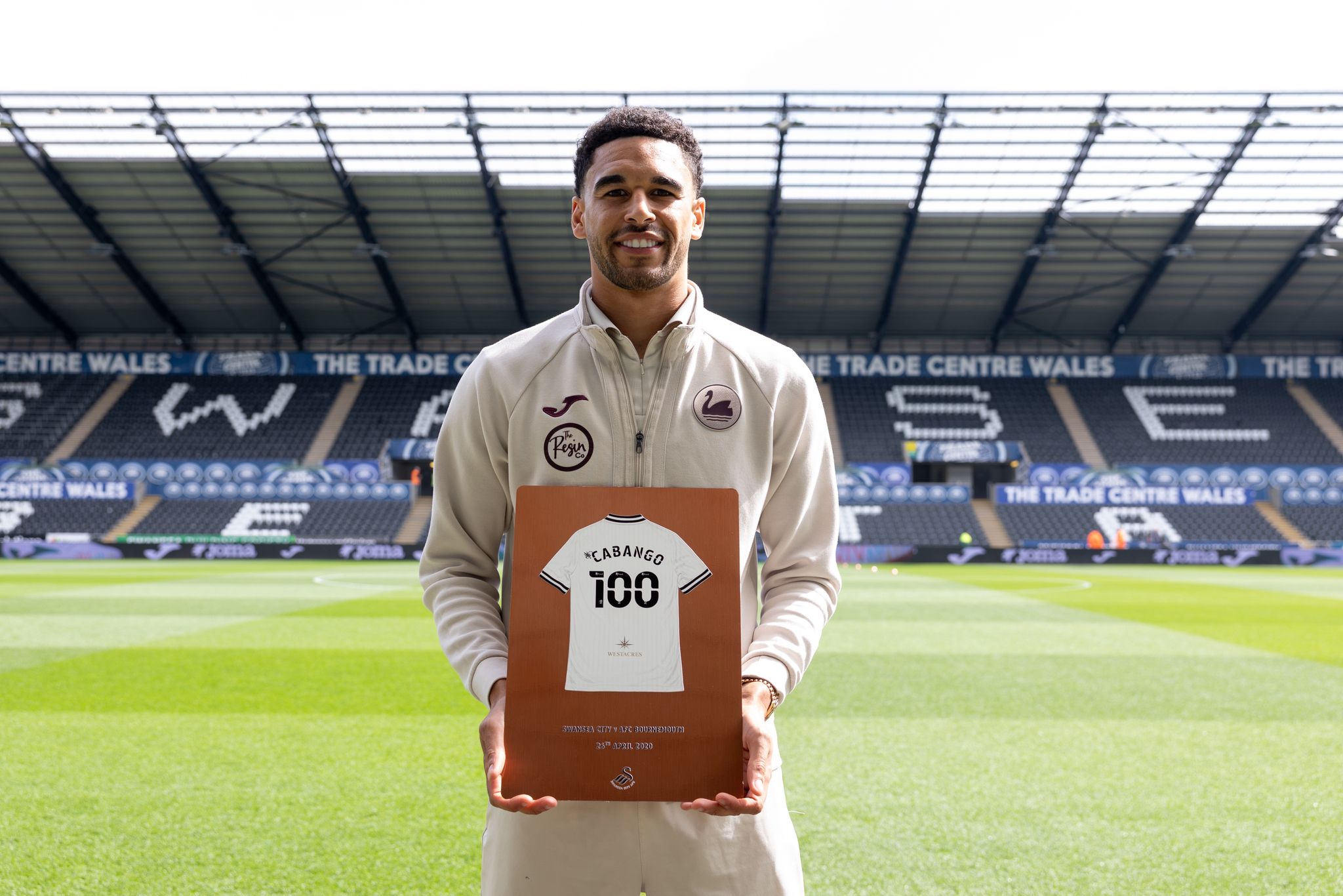 Ben Cabango holding his 100 appearance plaque on the pitch at the Swansea.com Stadium
