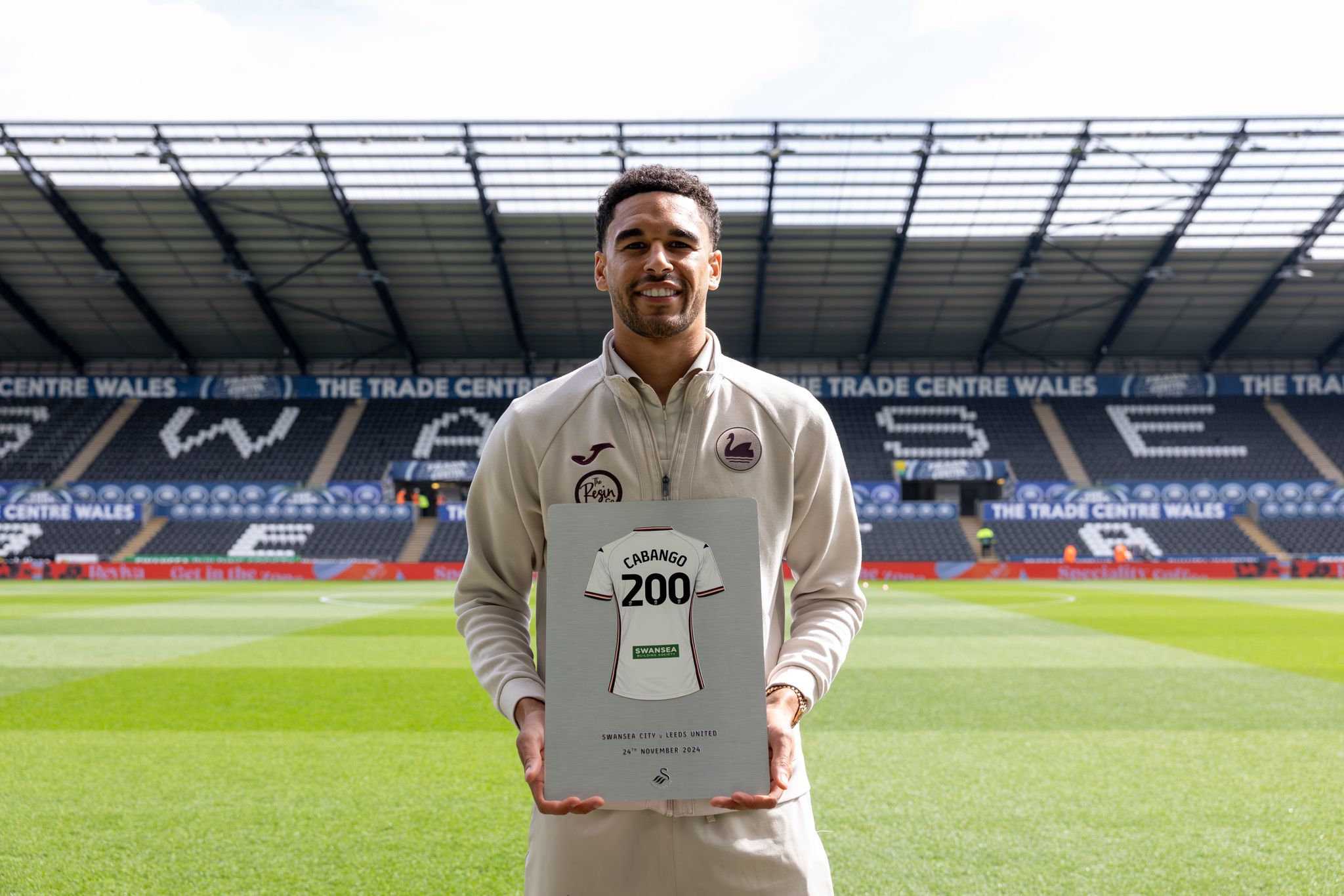 Ben Cabango holding his 200 appearance Silver finish plaque on the pitch at the Swansea.com Stadium