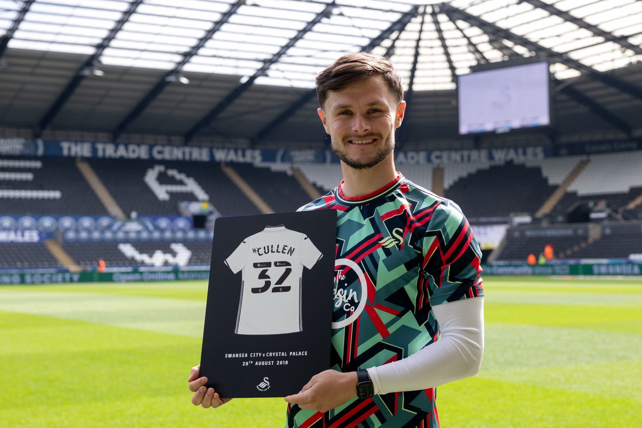 Liam Cullen holding his debut Black finish plaque on the pitch at the Swansea.com Stadium