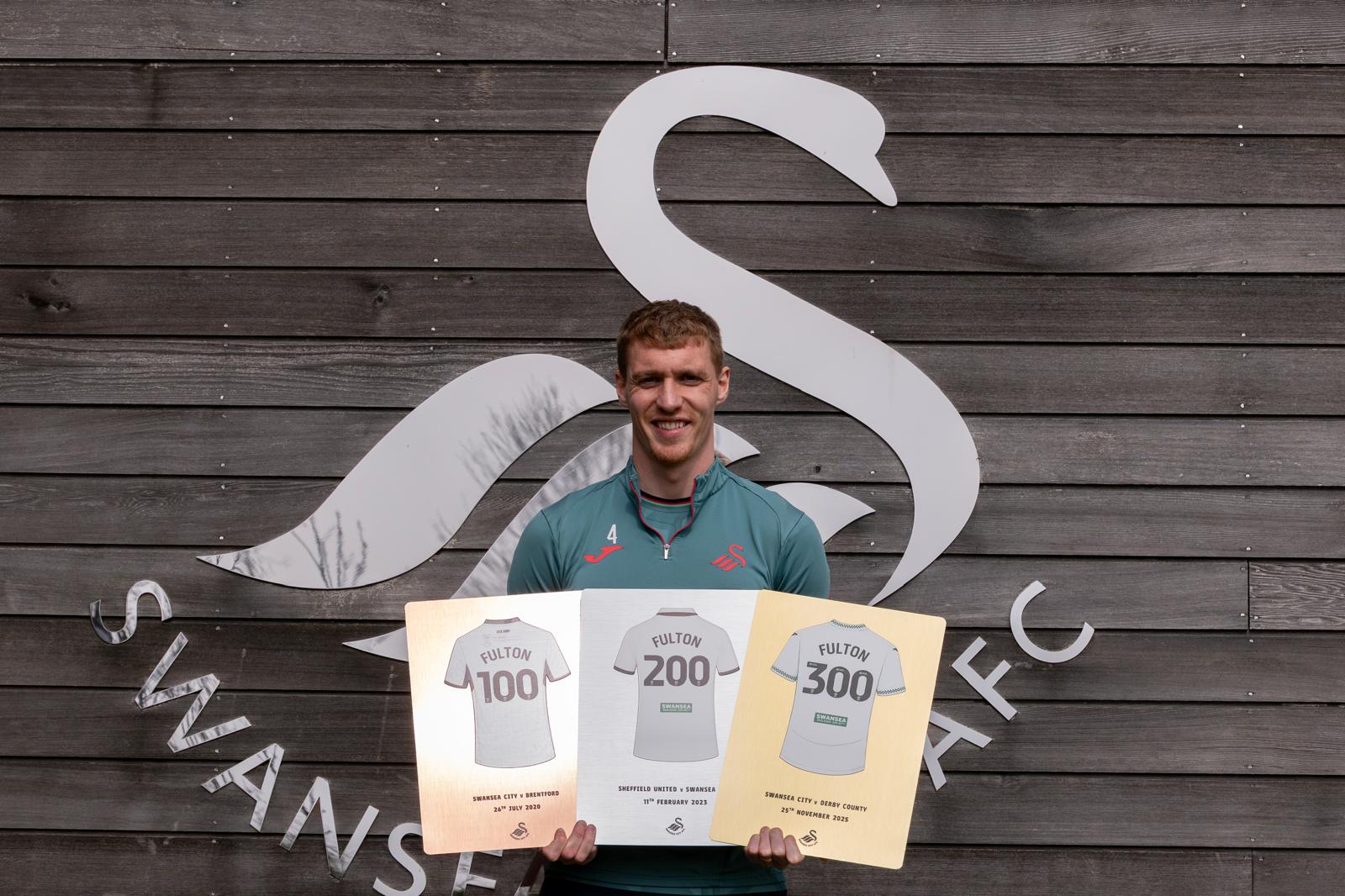 Jay Fulton holding his 100, 200 and 300 appearance plaques together, showing the Copper, Silver and Gold finish tiers